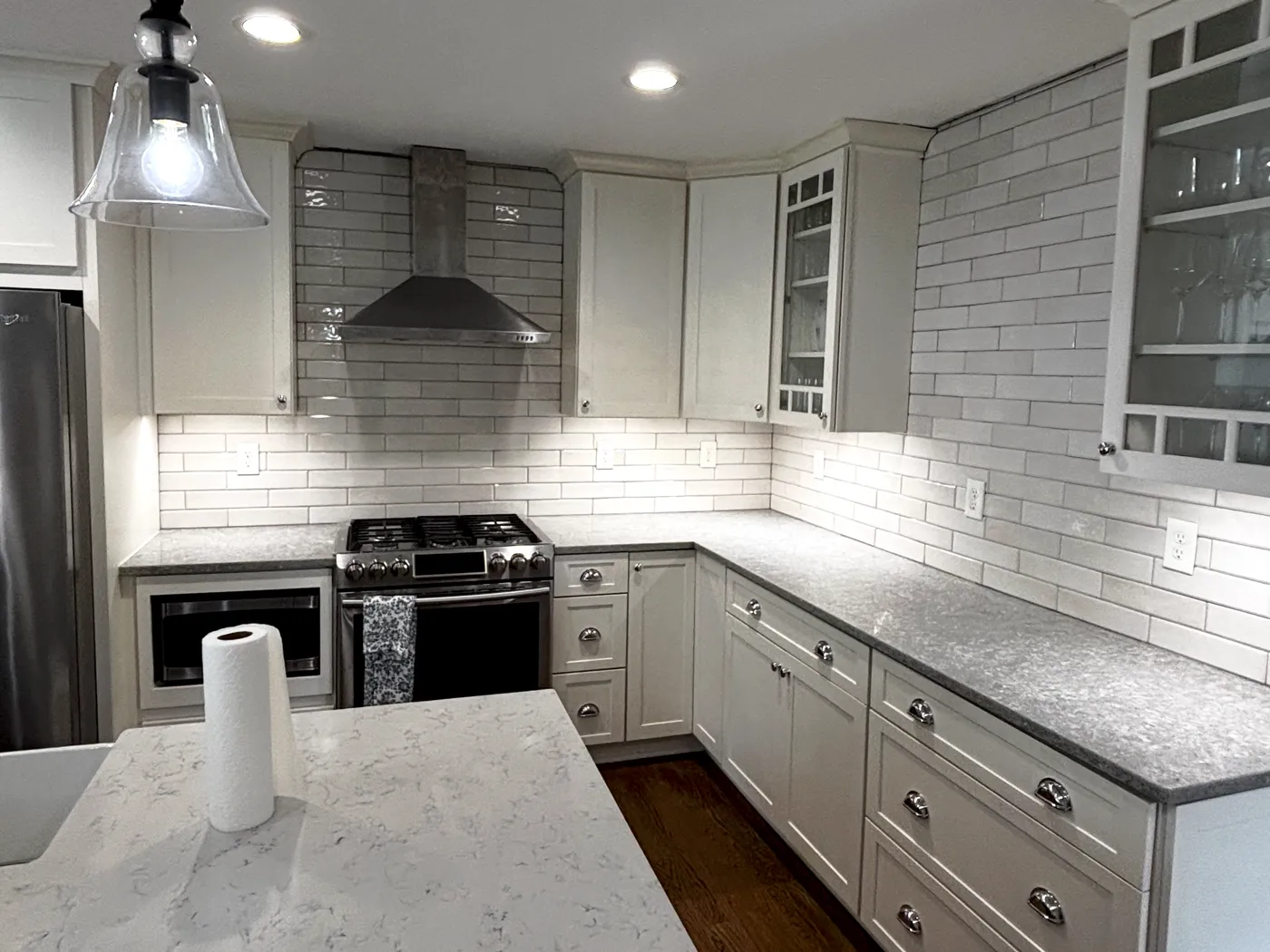 White shaker kitchen with quartz island, subway tile backsplash and stainless hood, a full cabinet replacement in Newnan, GA